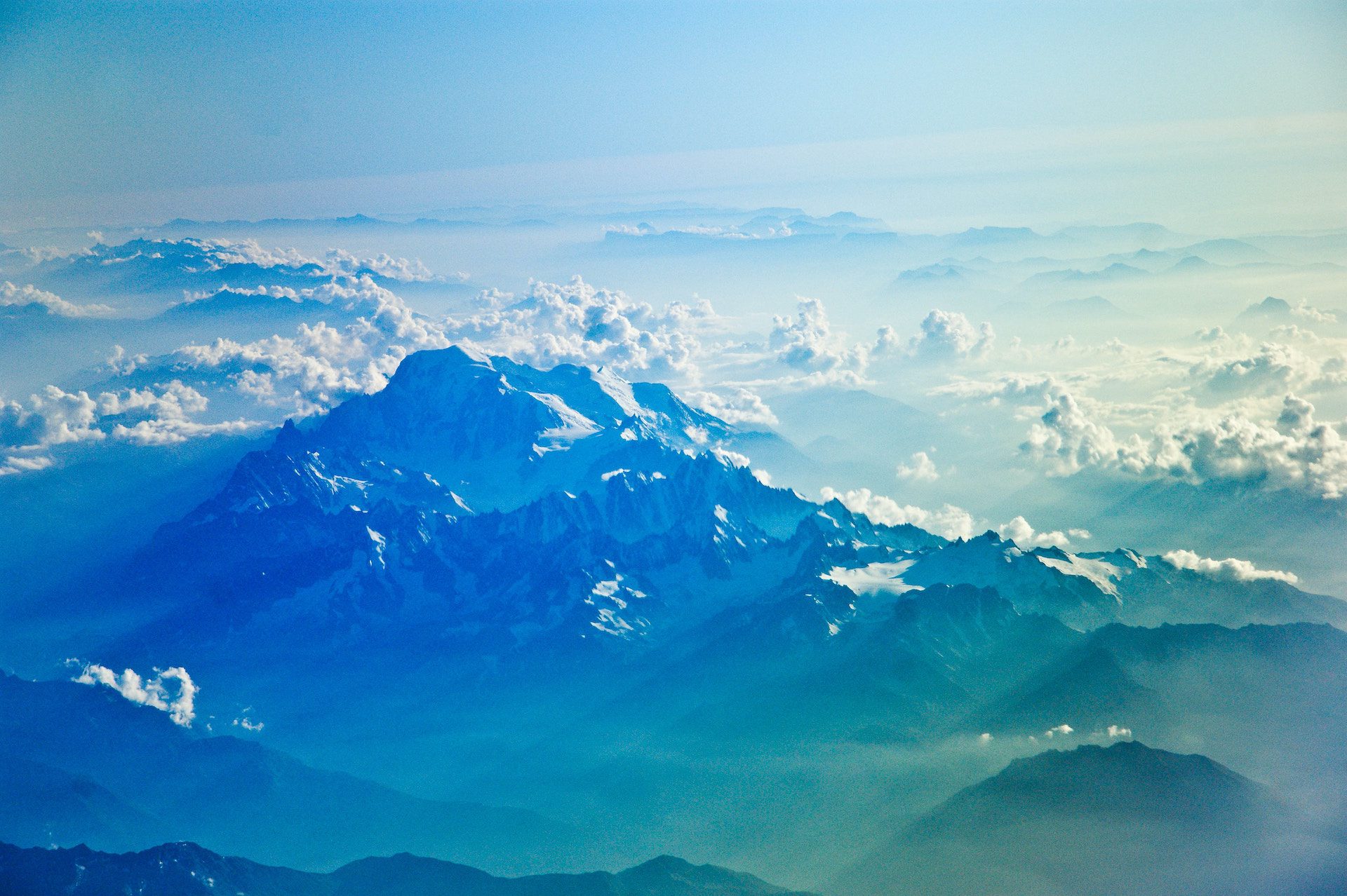 mountain peaks amongst a blue sky with clouds