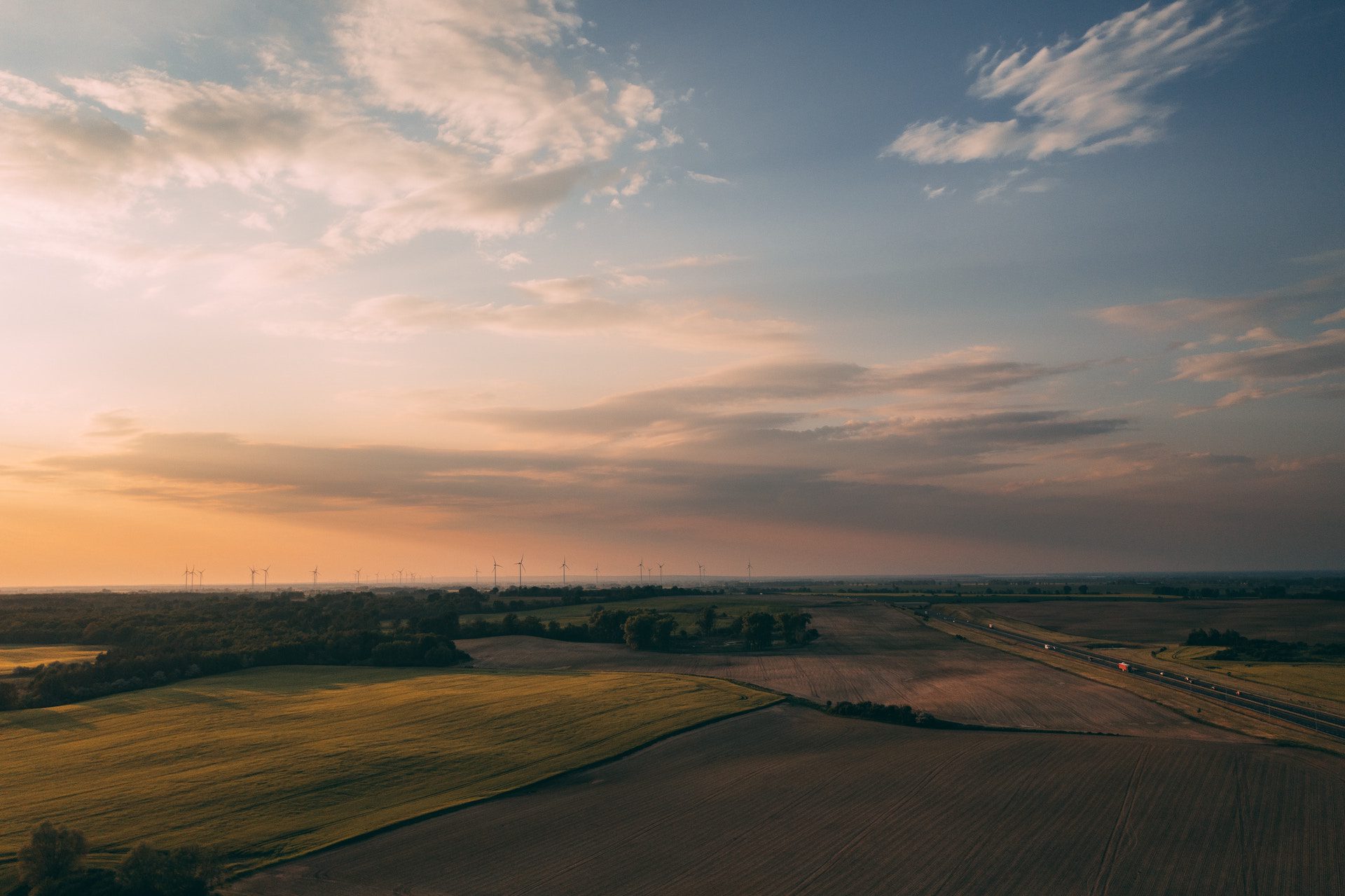 view of fields and a lake with a row of wind turbines in the distance
