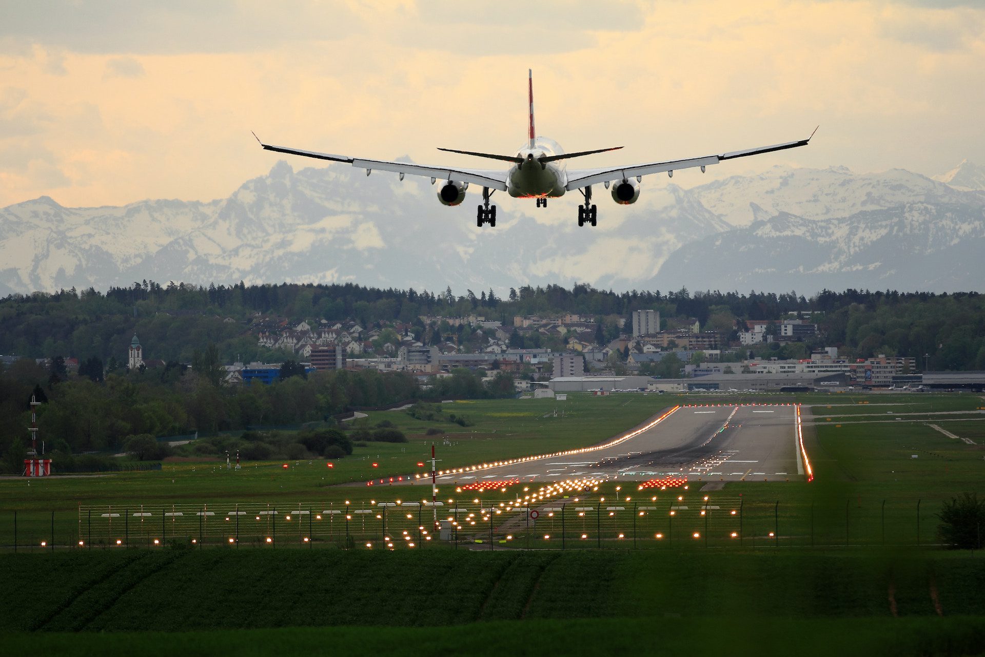 aeroplane taking off from a runway with view of mountains in the background and buildings