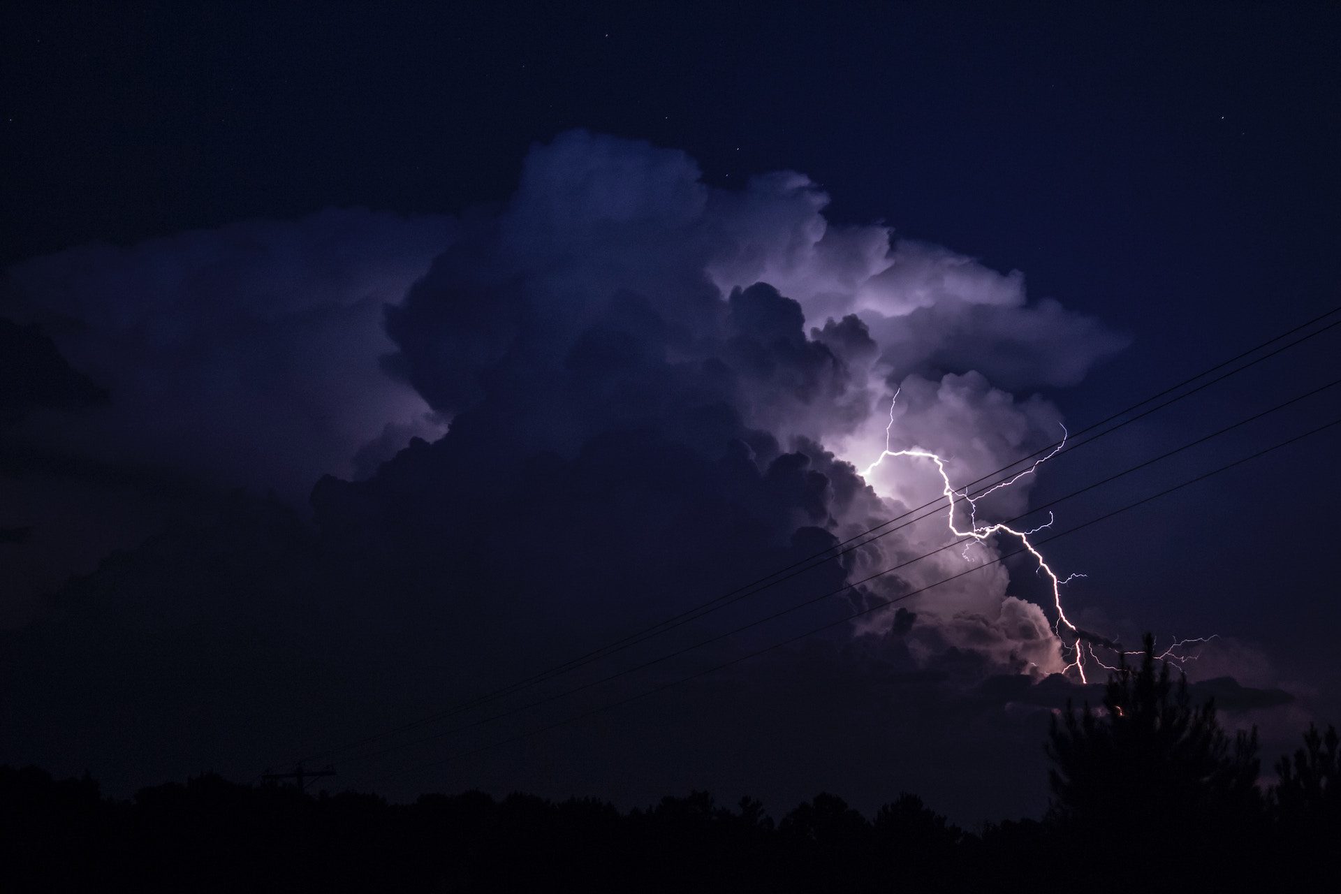 lightning bolt emerging through clouds at night