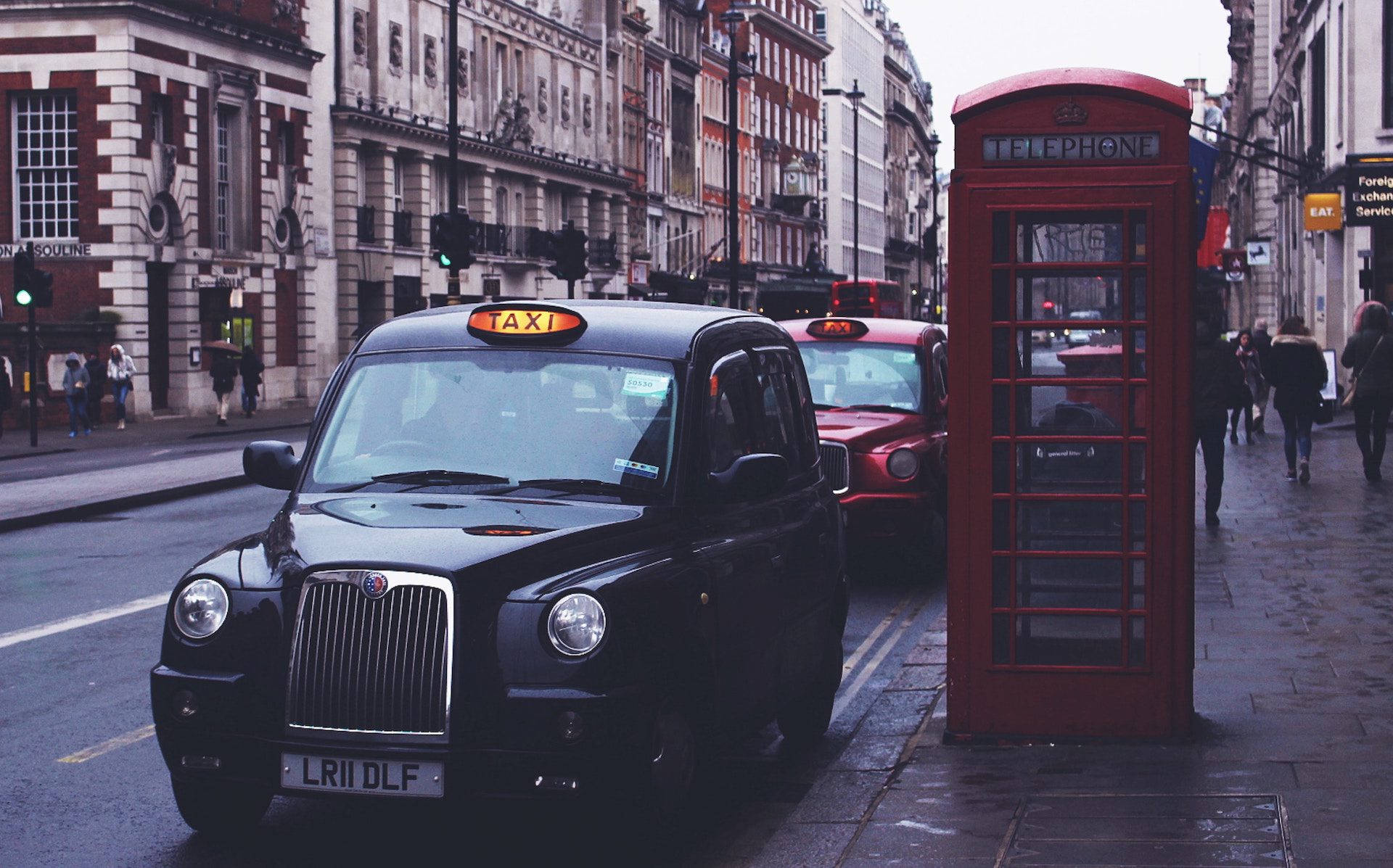 taxis parked on the road by a red telephone box in the city