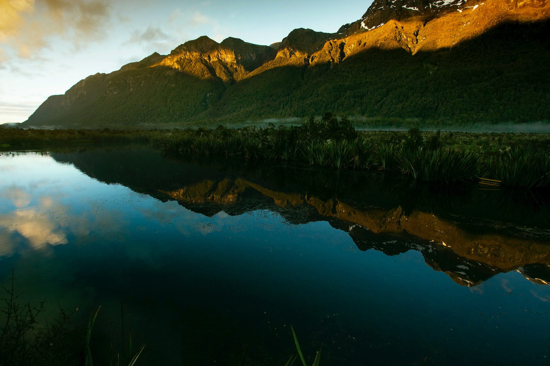 lake with grass and mountains either side and reflected in the lake