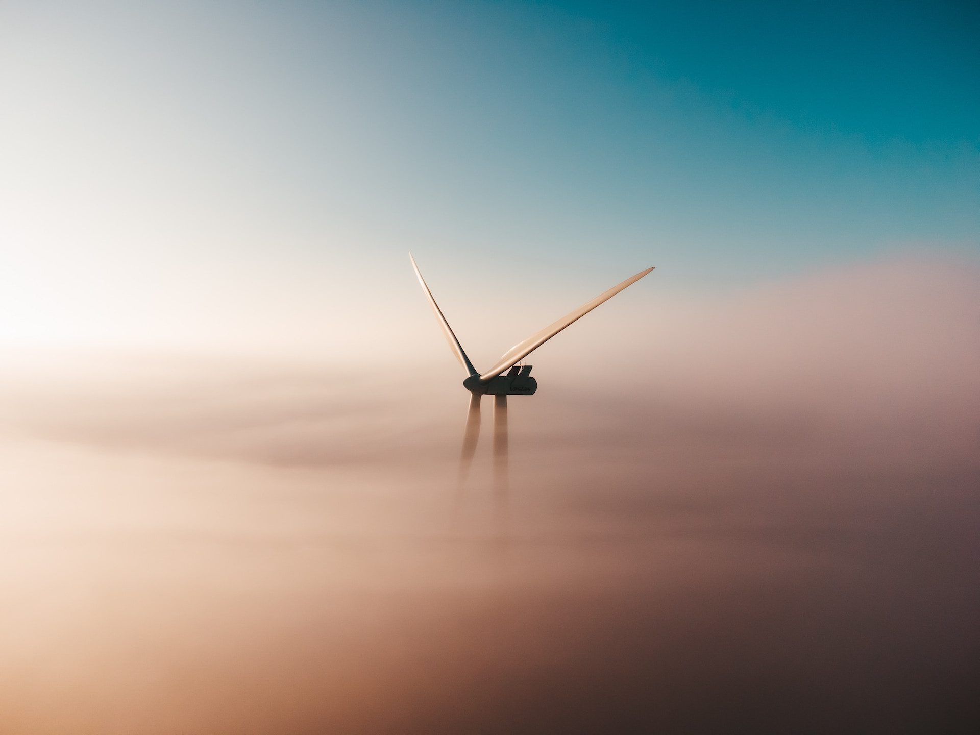view of a wind turbine peeking through clouds
